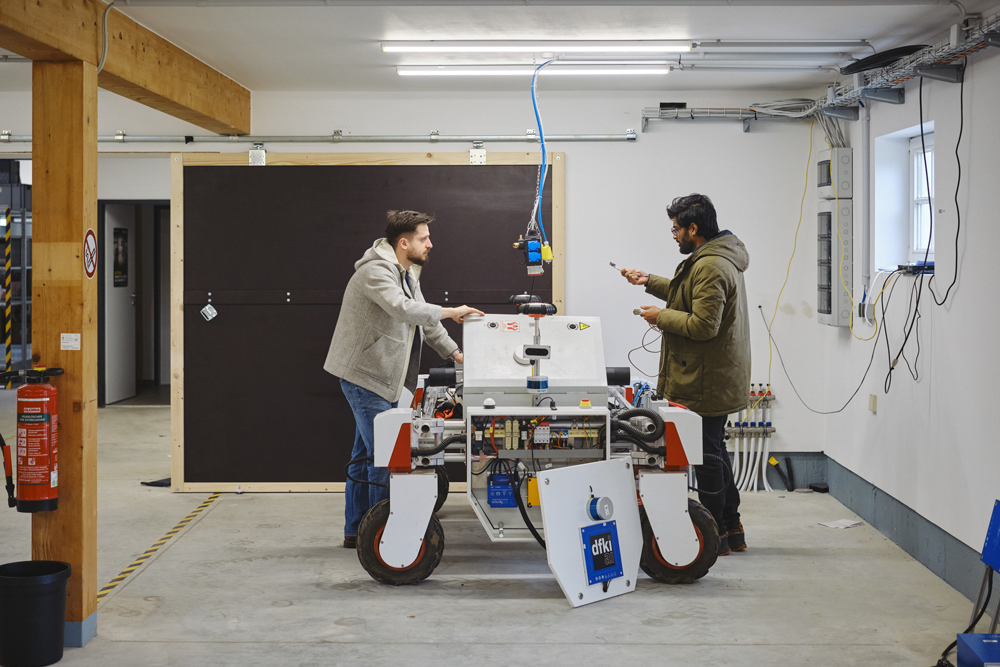 zwei Männer in einem Raum arbeiten an einem roboterartigen Gefährt