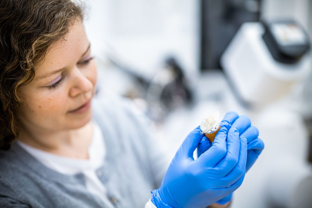 Forscherin schaut sich technisches Bauteil an